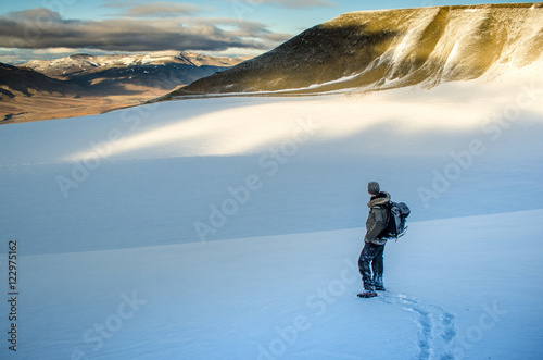 Adventurer at the edge of a glacier overlooking Arctic landscape