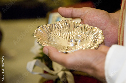 The priest's hands holding a silver salver with the rings during a Catholic wedding, Seville, Spain photo