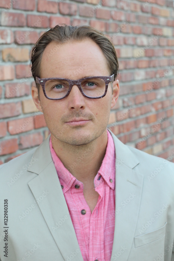Aged imposing businessman in beige suit and pink dress shirt. Isolated on urban brick wall background Aged imposing businessman in beige suit and pink dress shirt. Isolated on urban brick wall background