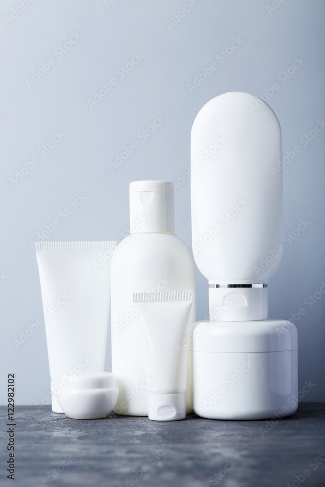 White cosmetic bottles on a grey table White cosmetic bottles on a grey table
