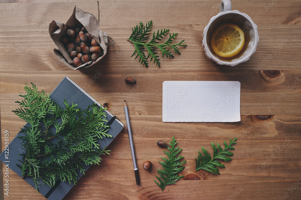 top view of notebook and pine branches with cup of tea with lemons