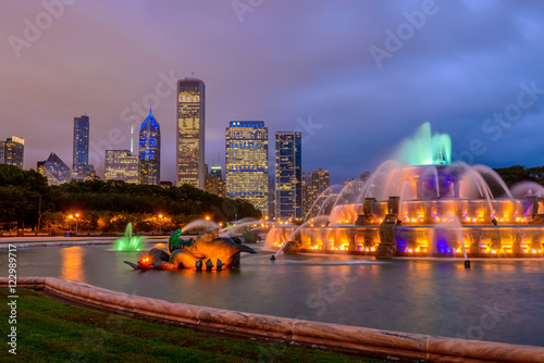 Chicago skyline panorama with skyscrapers and Buckingham fountain in Grant Park at night lit by colorful lights.