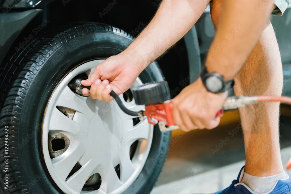 Fototapeta premium Man checking the tire pressure before a trip