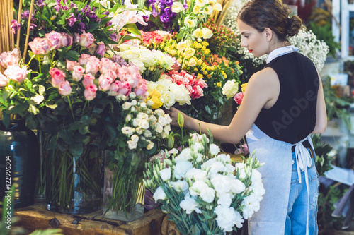 Rear view of female florist picking roses from potted plants photo