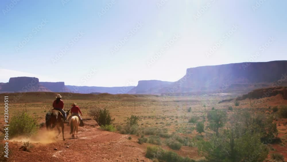 Cowboys riding their horses into a Desert Valley