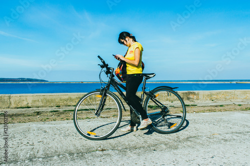 Outdoor portrait of pretty young girl riding bike and talking on the phone.