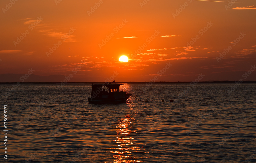 Fishing boat on sea at sunset, silhouette.