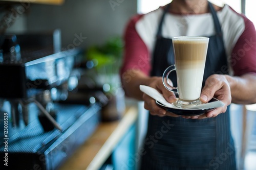 Waiter holding cup of cold coffee at counter in cafe