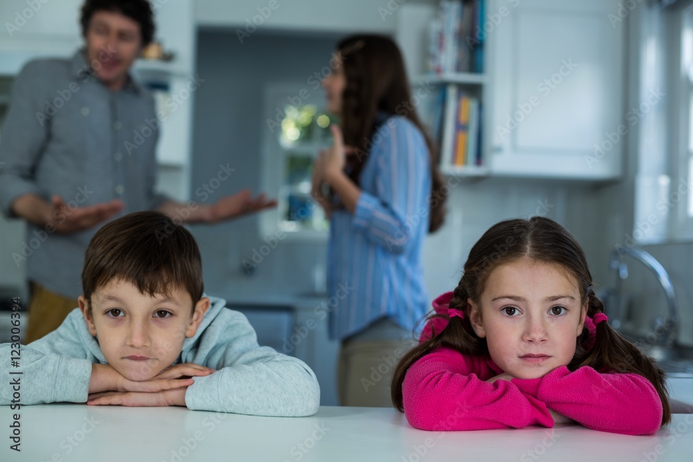 Upset children sitting while couple arguing with each other Upset children sitting while couple arguing with each other