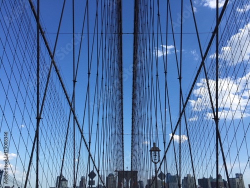 the symmetry of Brooklyn bridge cable and buildings with blue sky, New York