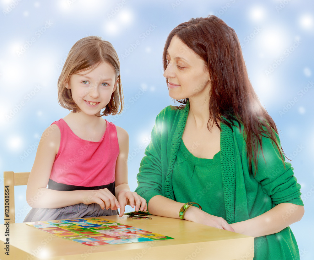Fototapeta premium The teacher and the girl at the table studying the cards