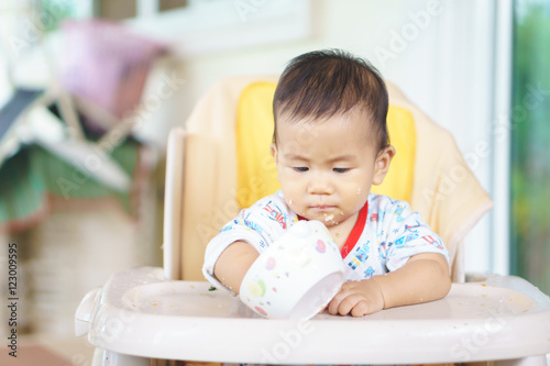 Asian baby eating food by himself