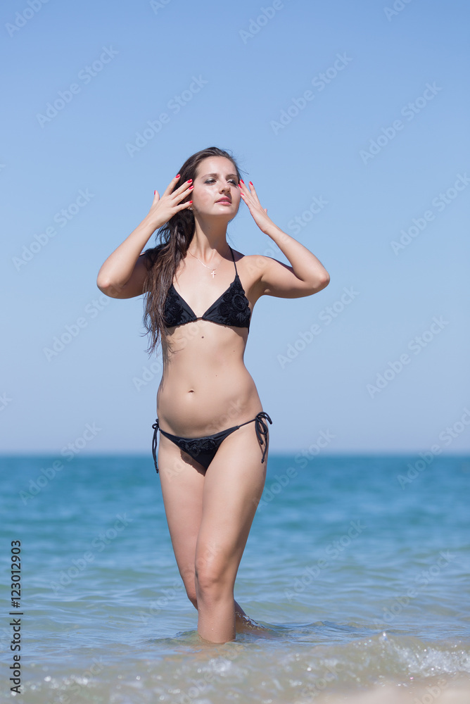 Girl stands in seawater with arms raised