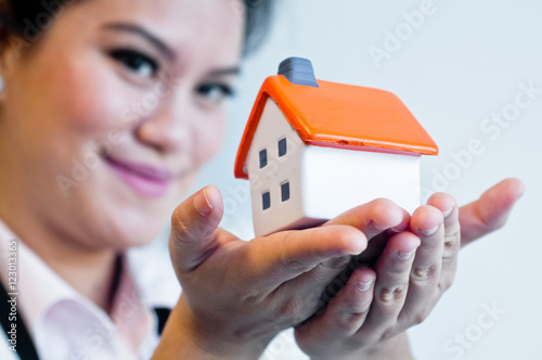 Woman hold a house model on white background
