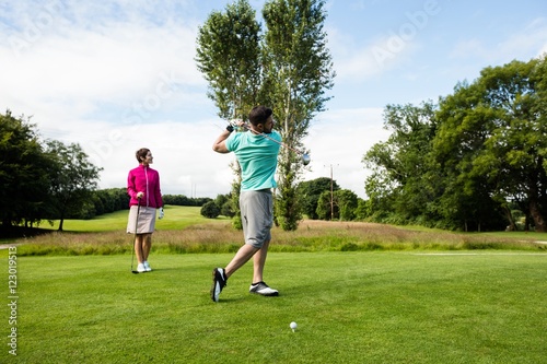 Męski instruktor pomaga kobiety w uczenie się golfa