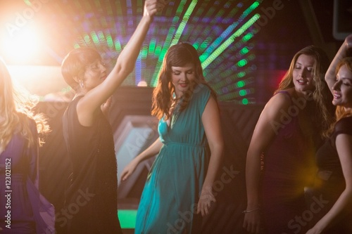 Group of smiling friends dancing on dance floor