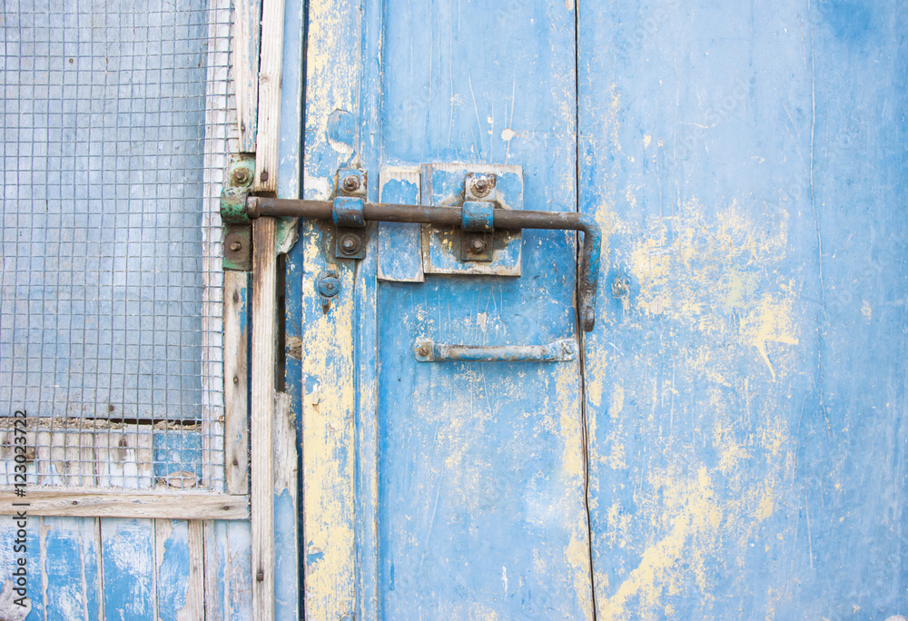Old latch on a wooden blue door in Tuscany, Italy.