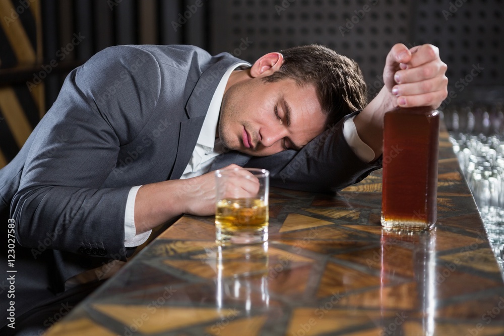 Drunk man lying on a counter with bottle of whisky Stock Photo | Adobe ...