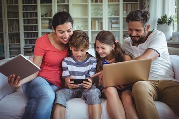 Happy family sitting on sofa and using laptop