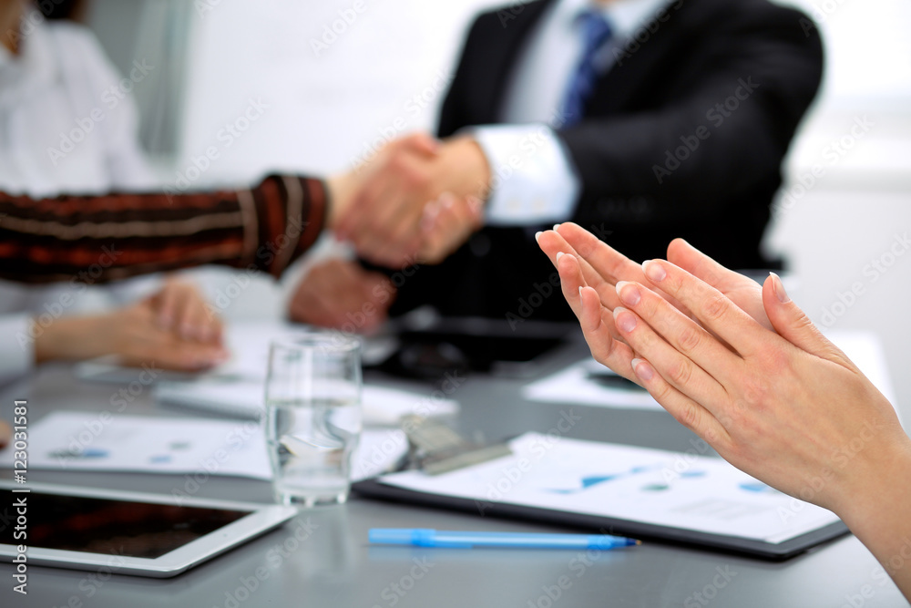 Close up of female applause while business people shaking hands at meeting Close up of female applause while business people shaking hands at meeting