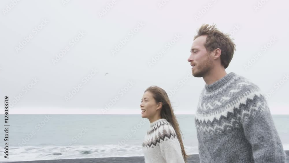 Couple on Iceland wearing Icelandic sweaters on black sand beach. Woman and man model in typical Icelandic sweater looking at ocean enjoying view of nature landscape at ocean sea. RED EPIC. Couple on Iceland wearing Icelandic sweaters on black sand beach. Woman and man model in typical Icelandic sweater looking at ocean enjoying view of nature landscape at ocean sea. RED EPIC.