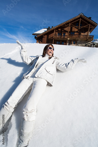 femme couchée dans la neige qui rit les bras en l'air photo