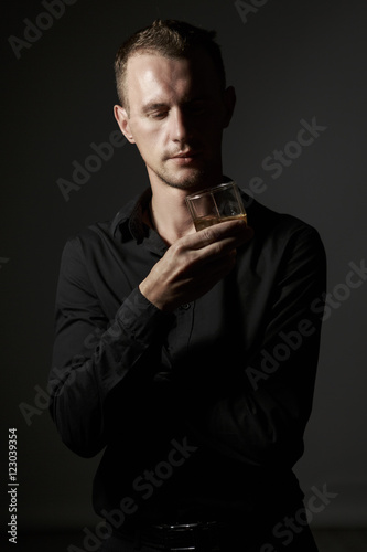 Portrait of a handsome man in a black shirt in the Studio with a Cup of tea