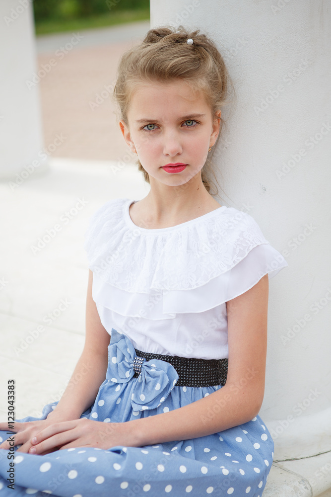 Fototapeta premium Portrait of beautiful young girl near the columns in the Park