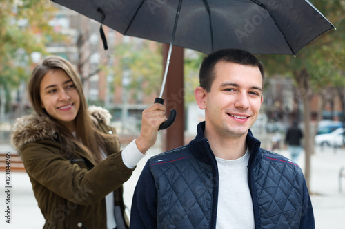 Young couple under umbrella .