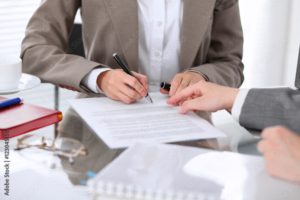 Group of business people and lawyers discussing contract sitting at the table. Woman chief is signing papers Group of business people and lawyers discussing contract sitting at the table. Woman chief is signing papers