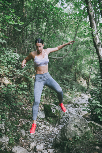 Attractive young woman doing stretching exercises in beautiful untouched nature environment.
