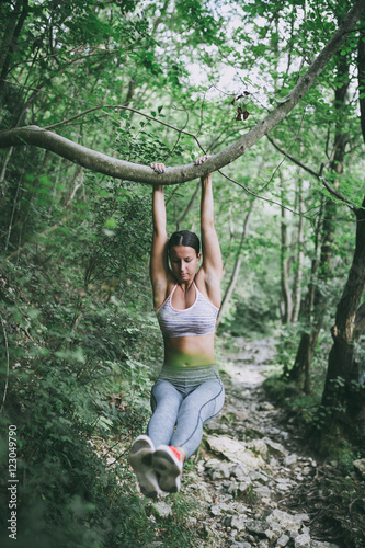 Attractive young woman doing stretching exercises in beautiful untouched nature environment.