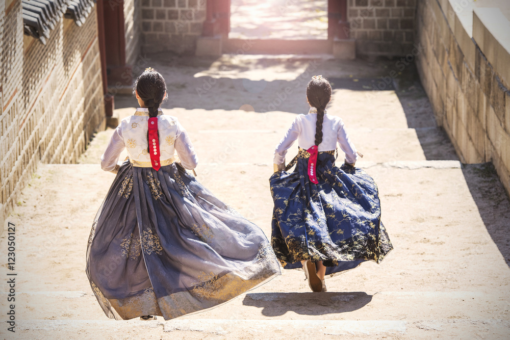 Fototapeta premium Dwie koreańskie dziewczyny ubrane w tradycyjne stroje zbiegające po schodach na ulicy Seulu