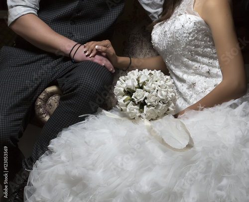 Canvas Print Bride and groom sitting holding hands on wedding day.