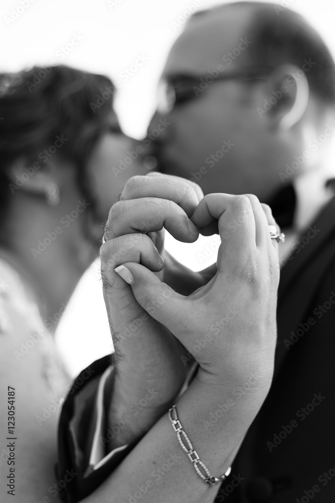 Hands of bride and groom in a shape of heart. Selective focus on