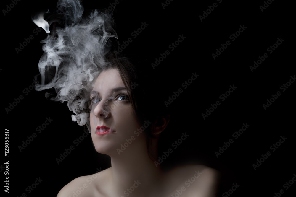 Woman blowing smoke against black background.