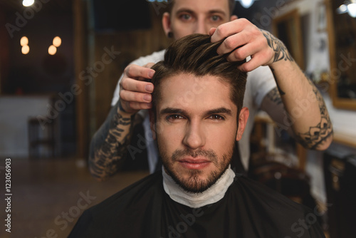 barber adjusts hair of a man