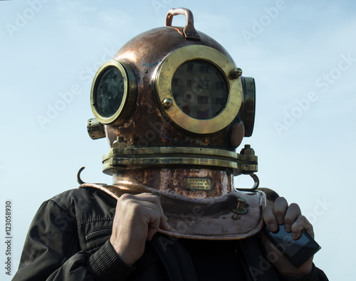 Man stands in his head to put on an old diving helmet photo