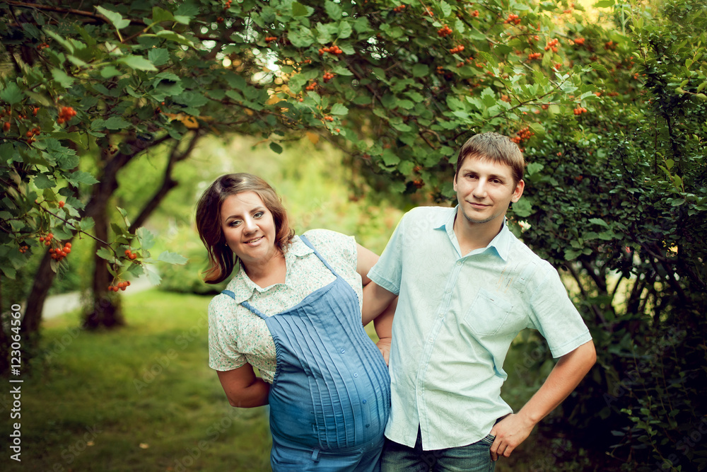 Fototapeta premium Happy couple expecting a baby walks in summer in a beautiful Par