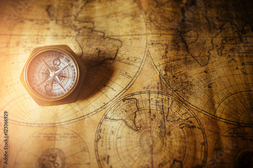 Close up of an old nautical compass on vintage map with sunshine
