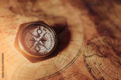 Close up of an old nautical compass on vintage map with sunshine