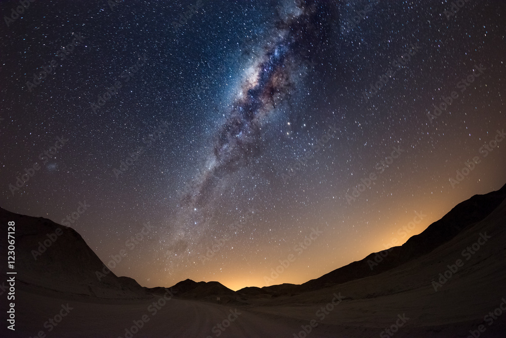Fototapeta premium Starry sky and Milky Way arc, with details of its colorful core, outstandingly bright, captured from the Namib desert in Namibia, Africa. The Small Magellanic Cloud on the left hand side.