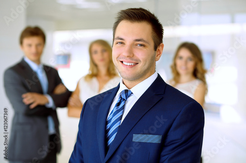 Smiling businessman  in office with colleagues in the background © volha_r