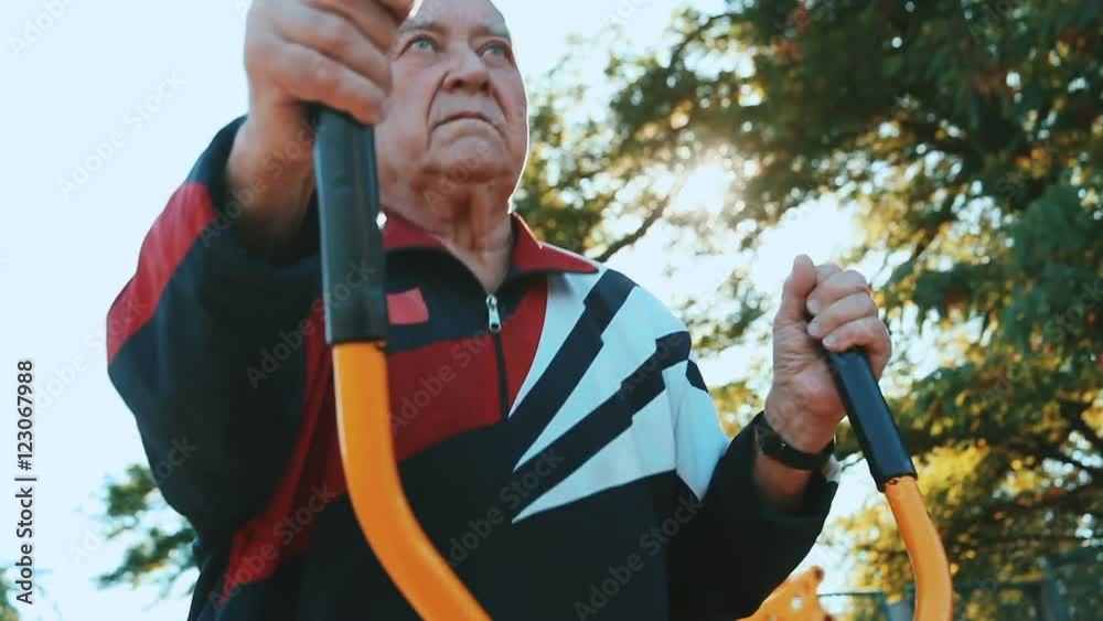 Elderly man exercising with fitness equipment in public outdoor gym.