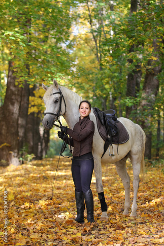 Equestrian girl with her horse in autumnal nature 