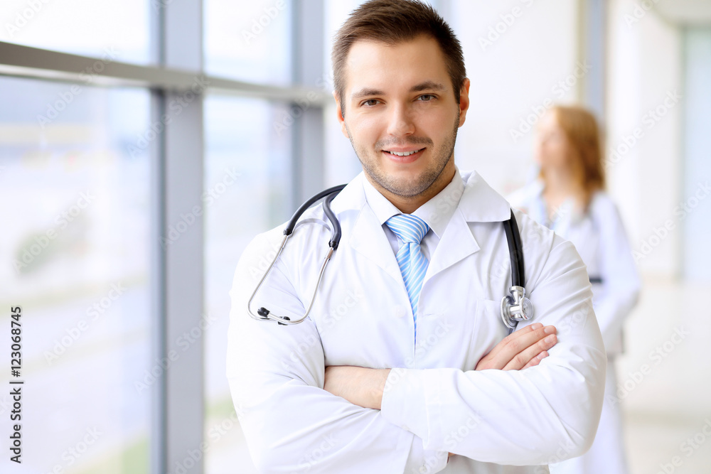 Smiling doctor waiting for his team while standing upright Smiling doctor waiting for his team while standing upright
