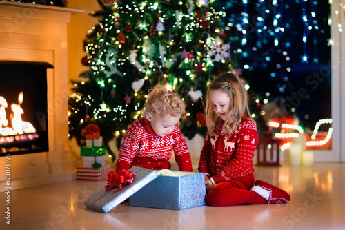 Kids opening Christmas presents at fireplace © famveldman