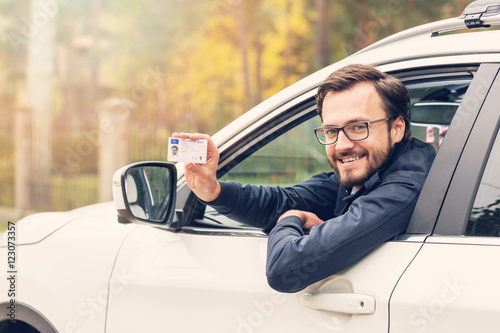 Konstfotografi man sitting in the car and showing his driver license