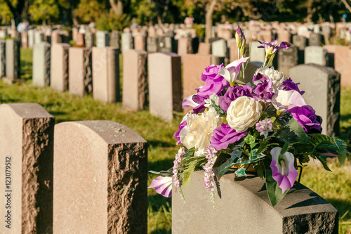 Flowers in a cemetery with headstones in the background at sunset