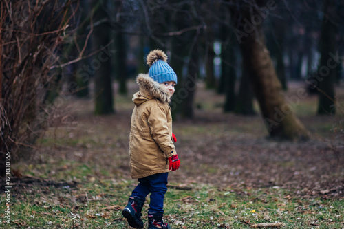 Cute little baby boy walking away in autumn park